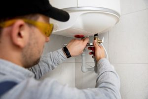 K L Contractor Plumbing Inc | 7 Signs Your Water Heater Is Failing Worker repairing water heater 1 1