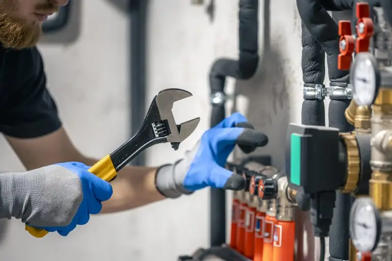 A man installs a heating system in a house and checks the pipes with a wrench. Man installs heating system house checks pipes with wrench 1